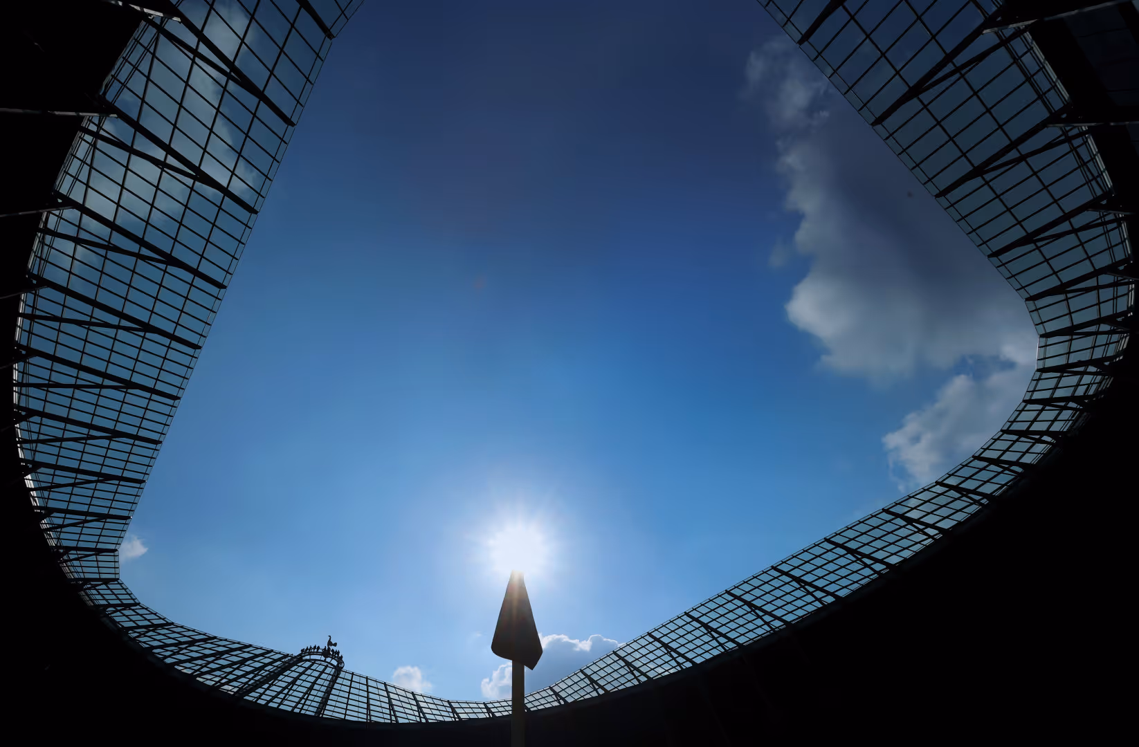 The Tottenham Hotspur Stadium is backlit by the sun.