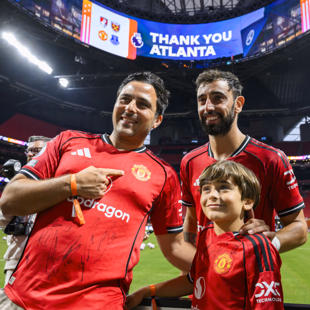 Bruno Fernandes takes a photo with an adult and a child fan in Atlanta.