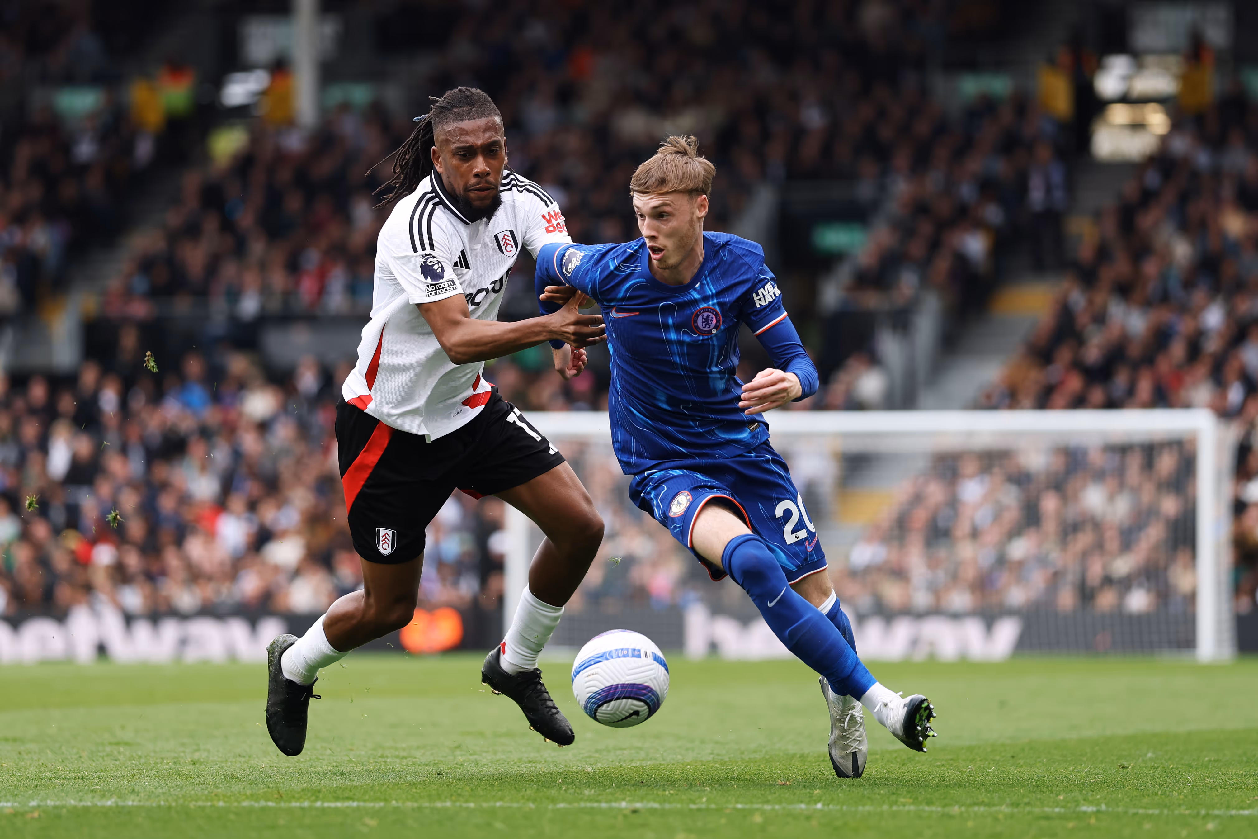 Fulham's Alex Iwobi challenges Chelsea's Cole Palmer for the ball.