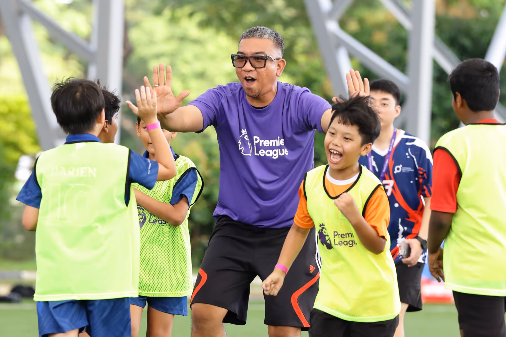 A coach high-fives local children during a coaching session in Singapore.