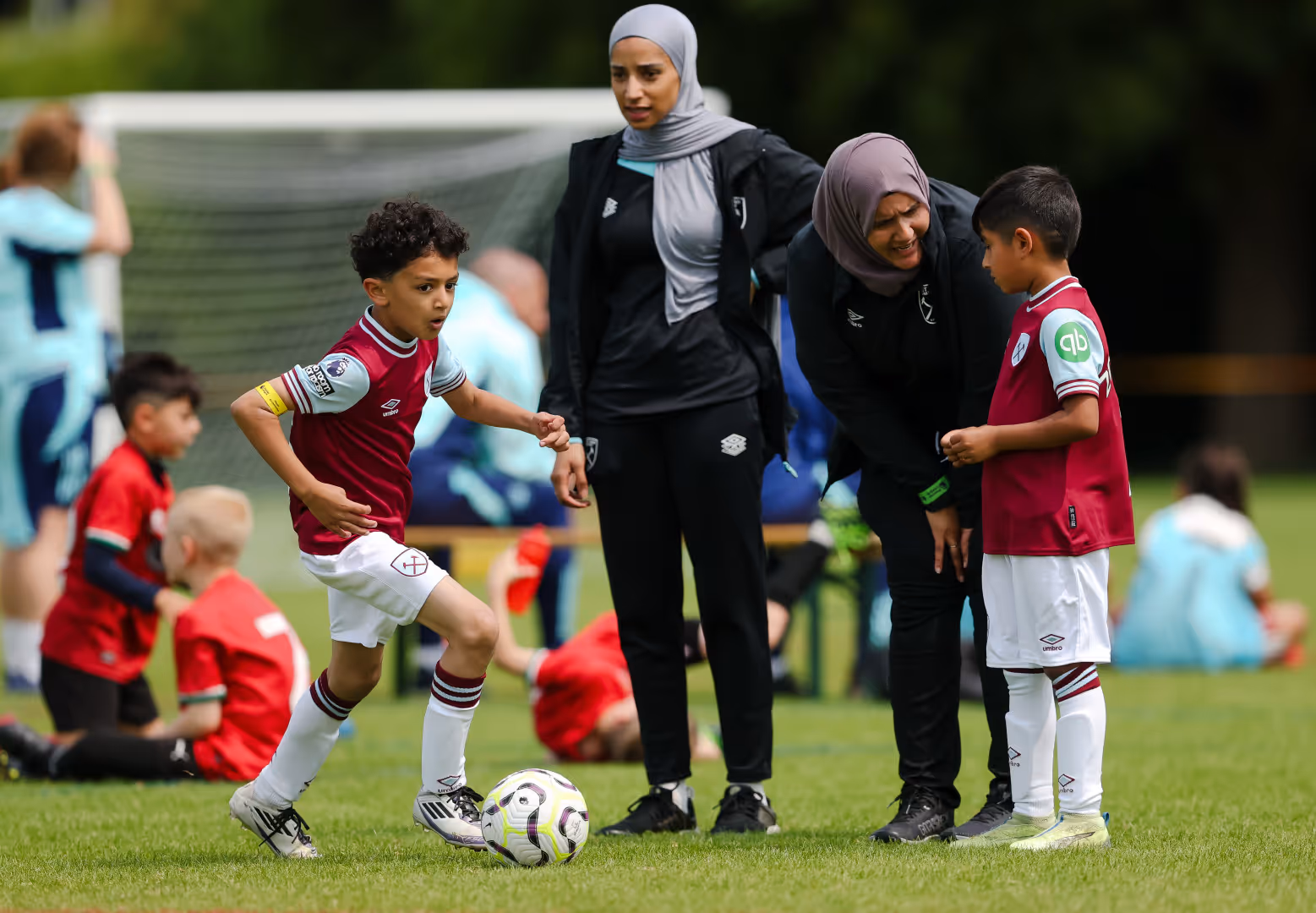 Two coaches from West Ham speak with two children at a South Asian Action Plan Emerging Talent Festival.
