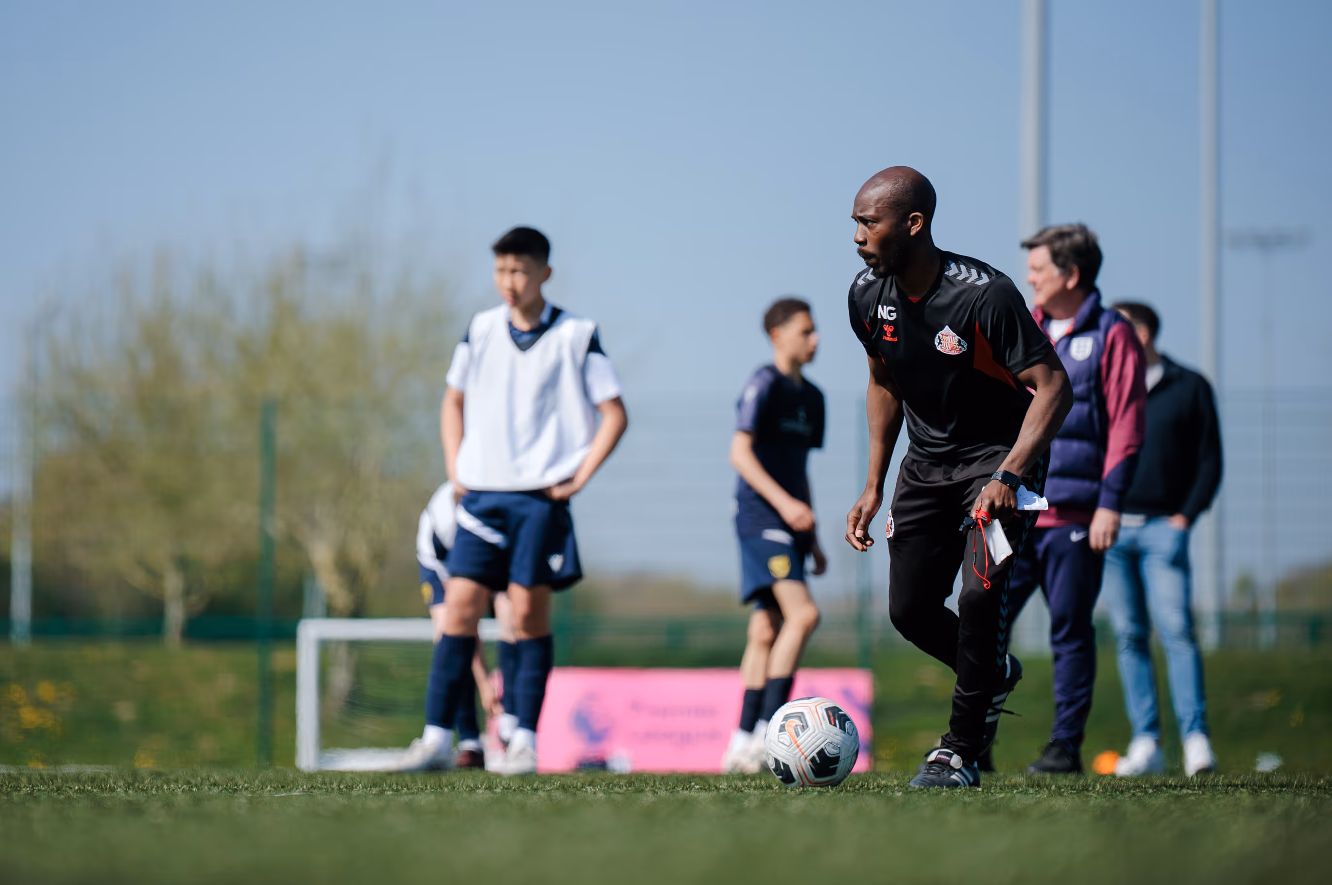 Football Coach running a drill on a pitch.