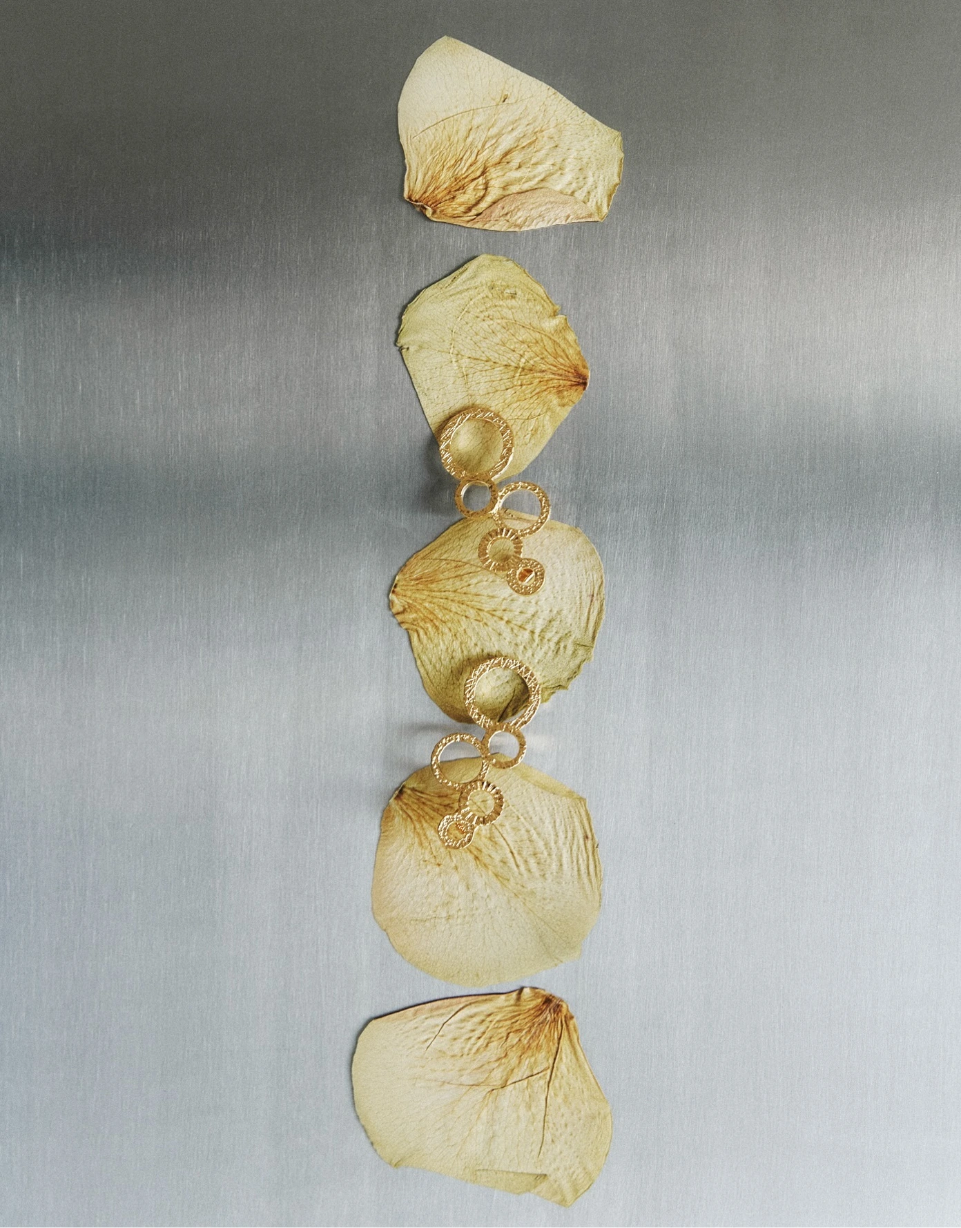 Product still — gold earrings with botanical petals