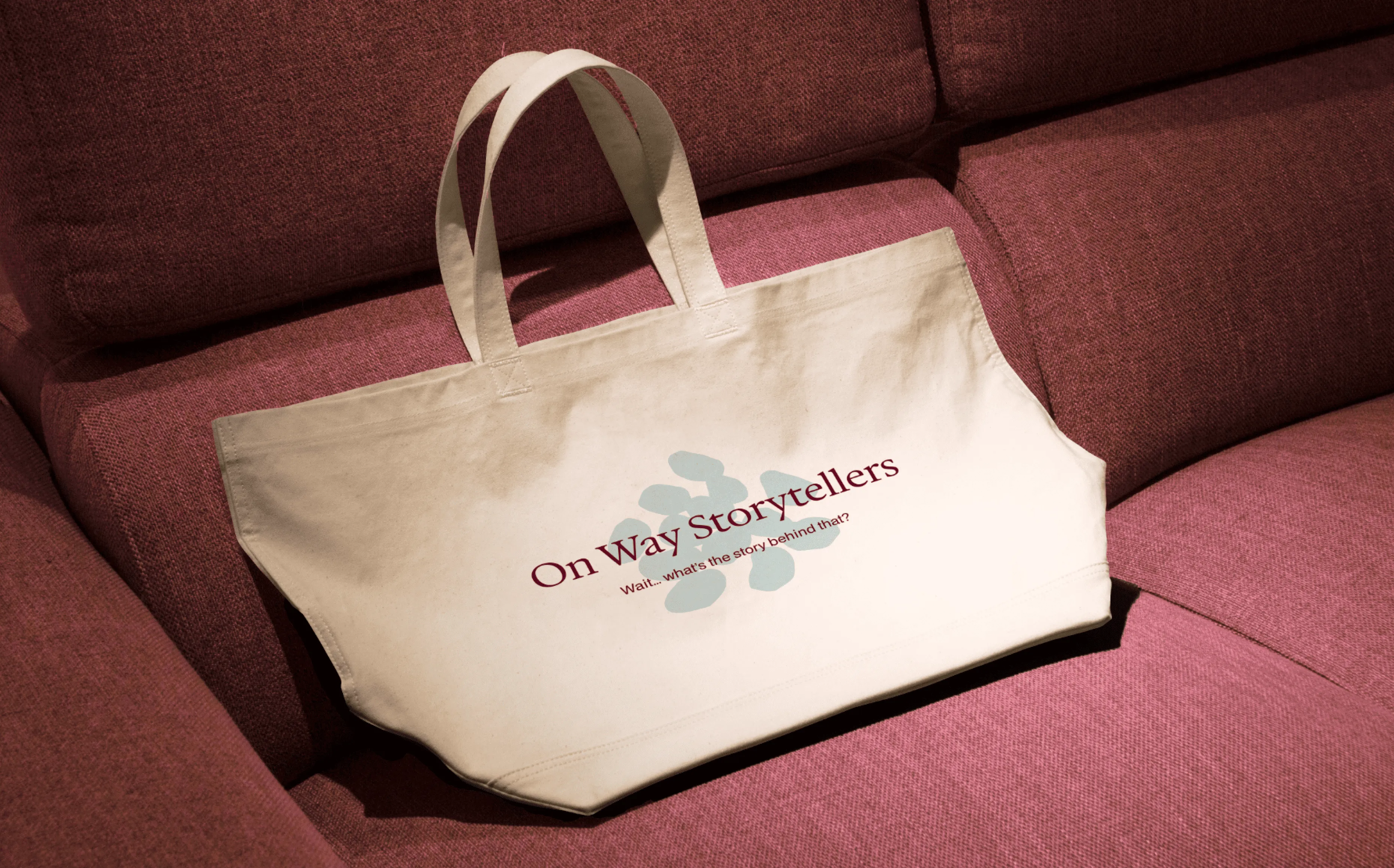 Tote bag with the On Way Storytellers logo on a sofa.