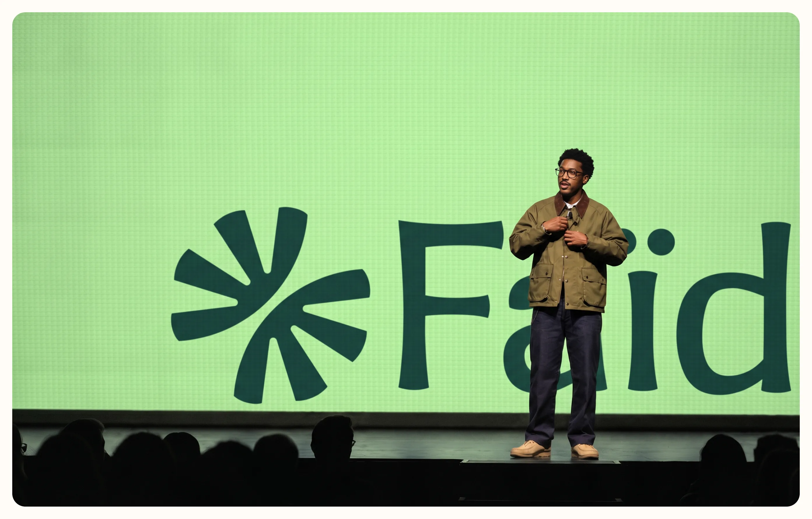 Speaker on stage in front of a large Faïda logo screen