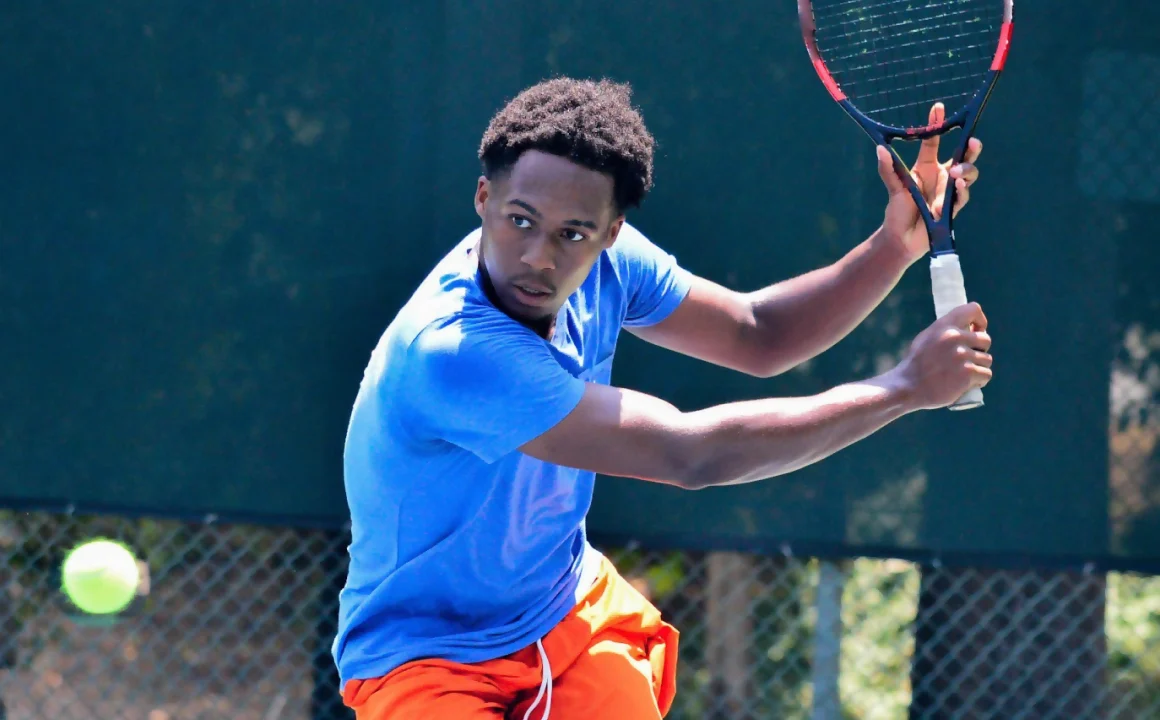 Three women sitting together indoors, smiling and holding tennis rackets.