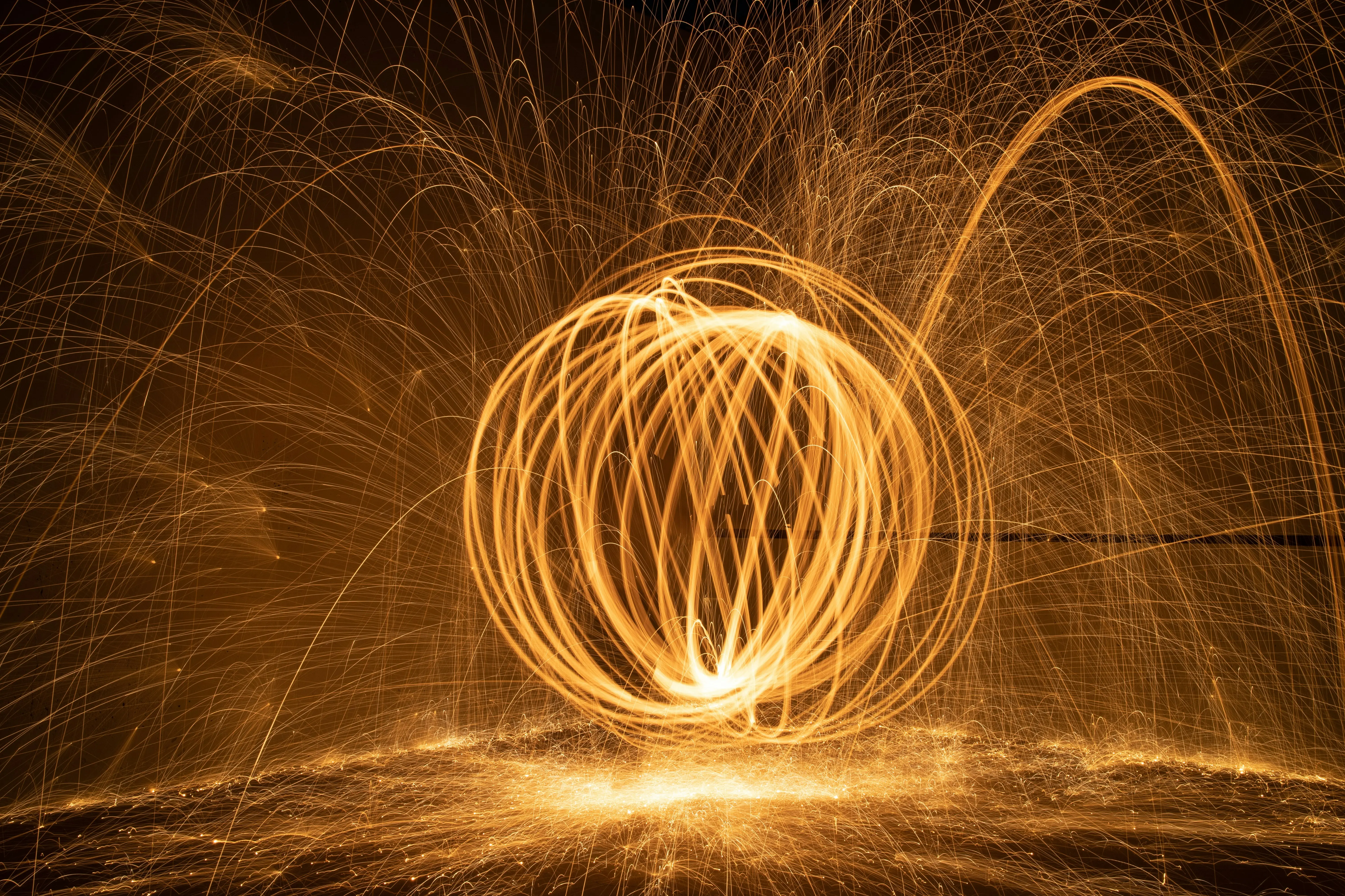 Orbe lumineuse de longues traînées lumineuses orange lumineux en mouvement circulaire crée un effet d'étincelles éclatantes dans l'obscurité.