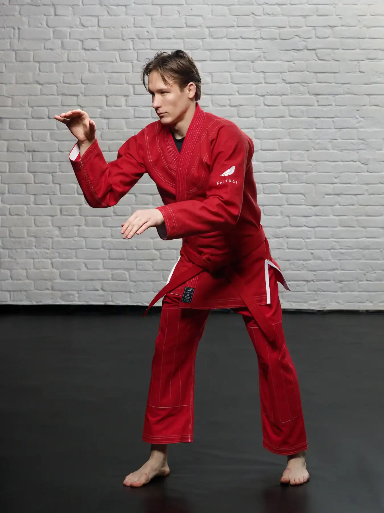 Борец в активной стойке в красном ги KAITOGI с белыми элементами