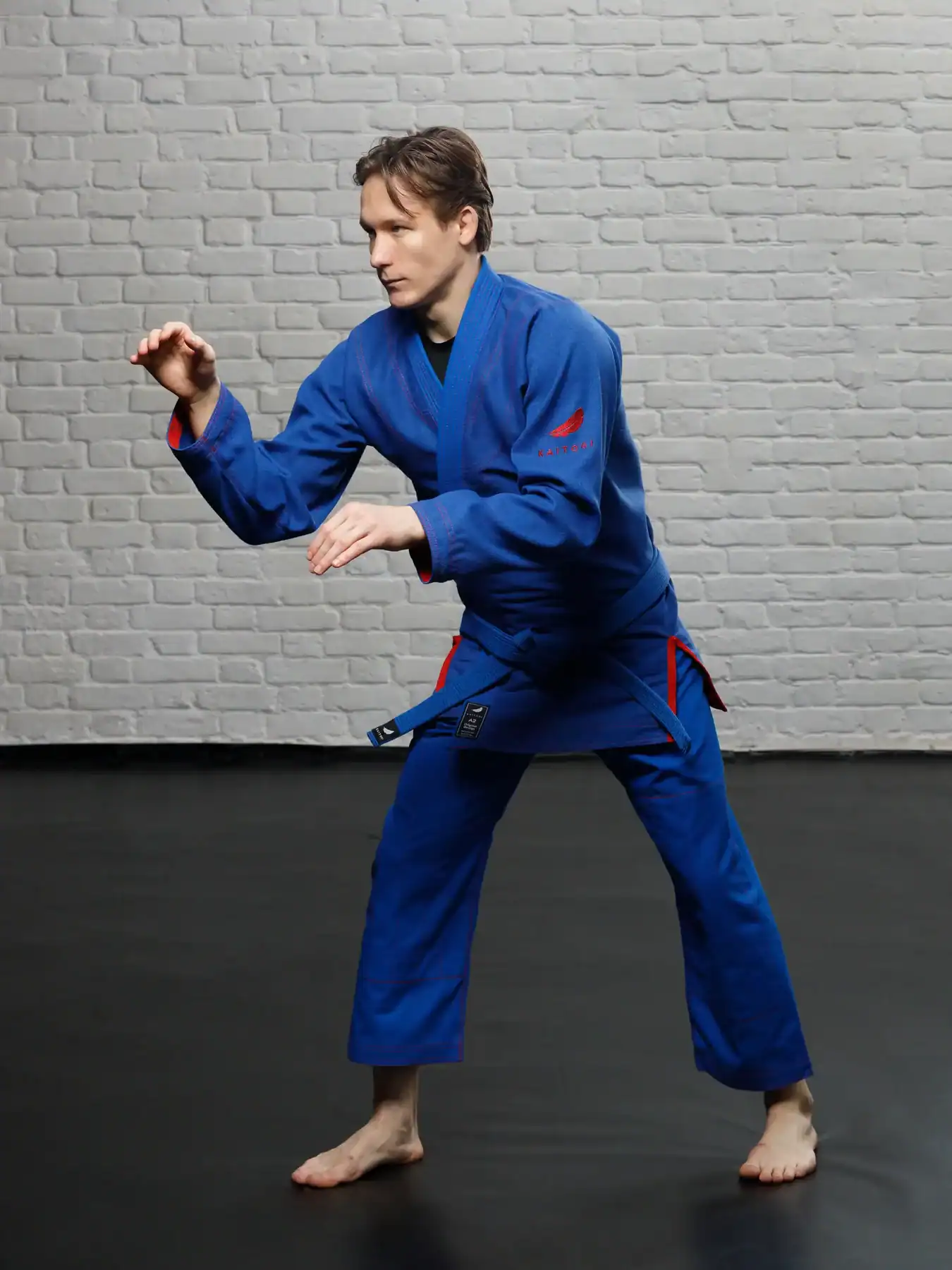 Спортсмен в синем кимоно KAITOGI с красным дизайном, готовый к схватке по грэпплингу