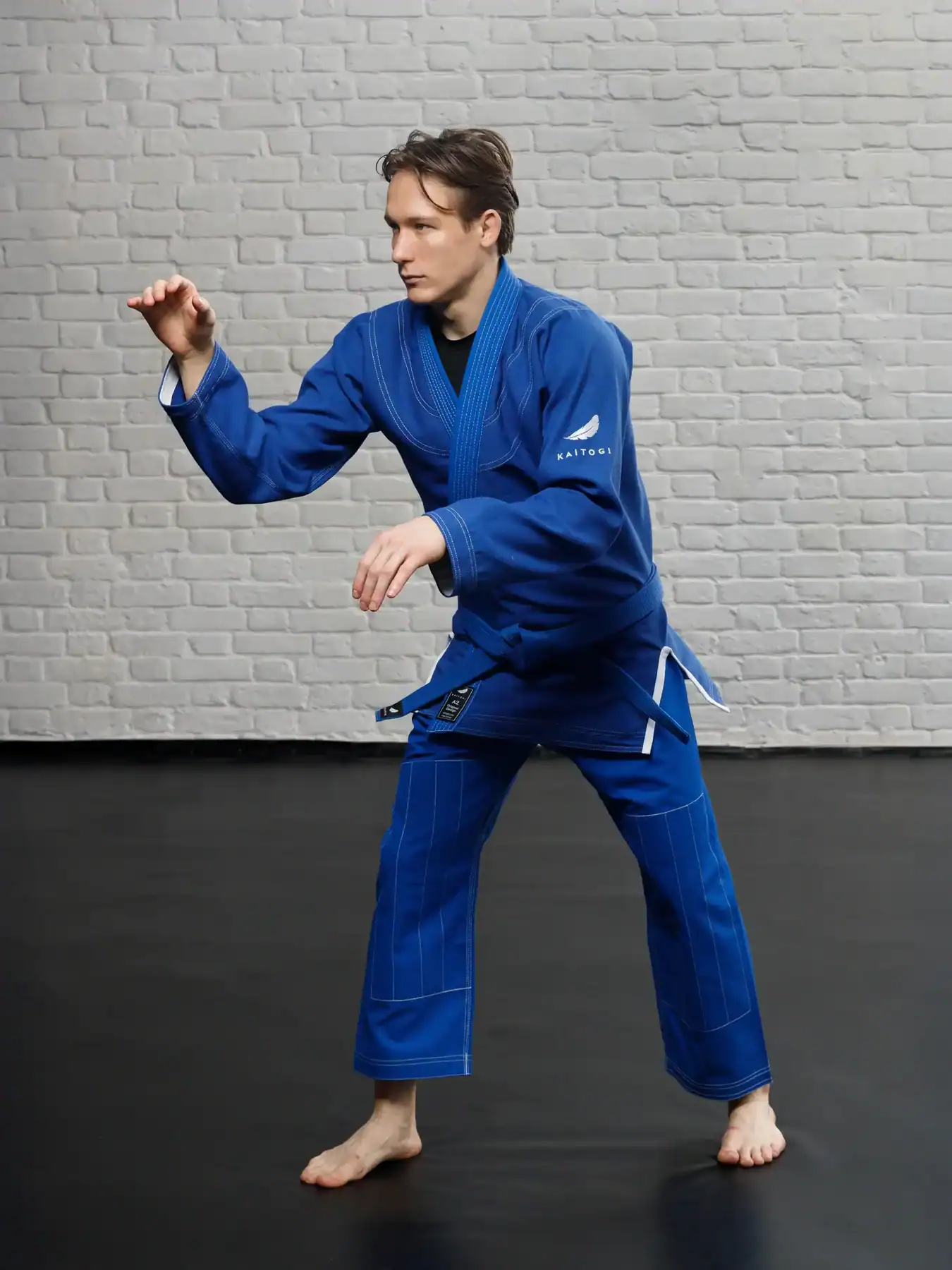 Грэпплер в классическом сине-белом ги KAITOGI, демонстрация посадки в стойке