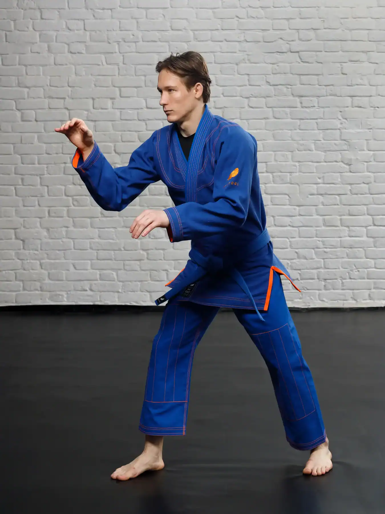 Демонстрация синего ги KAITOGI с оранжевой строчкой: борец в стойке на татами