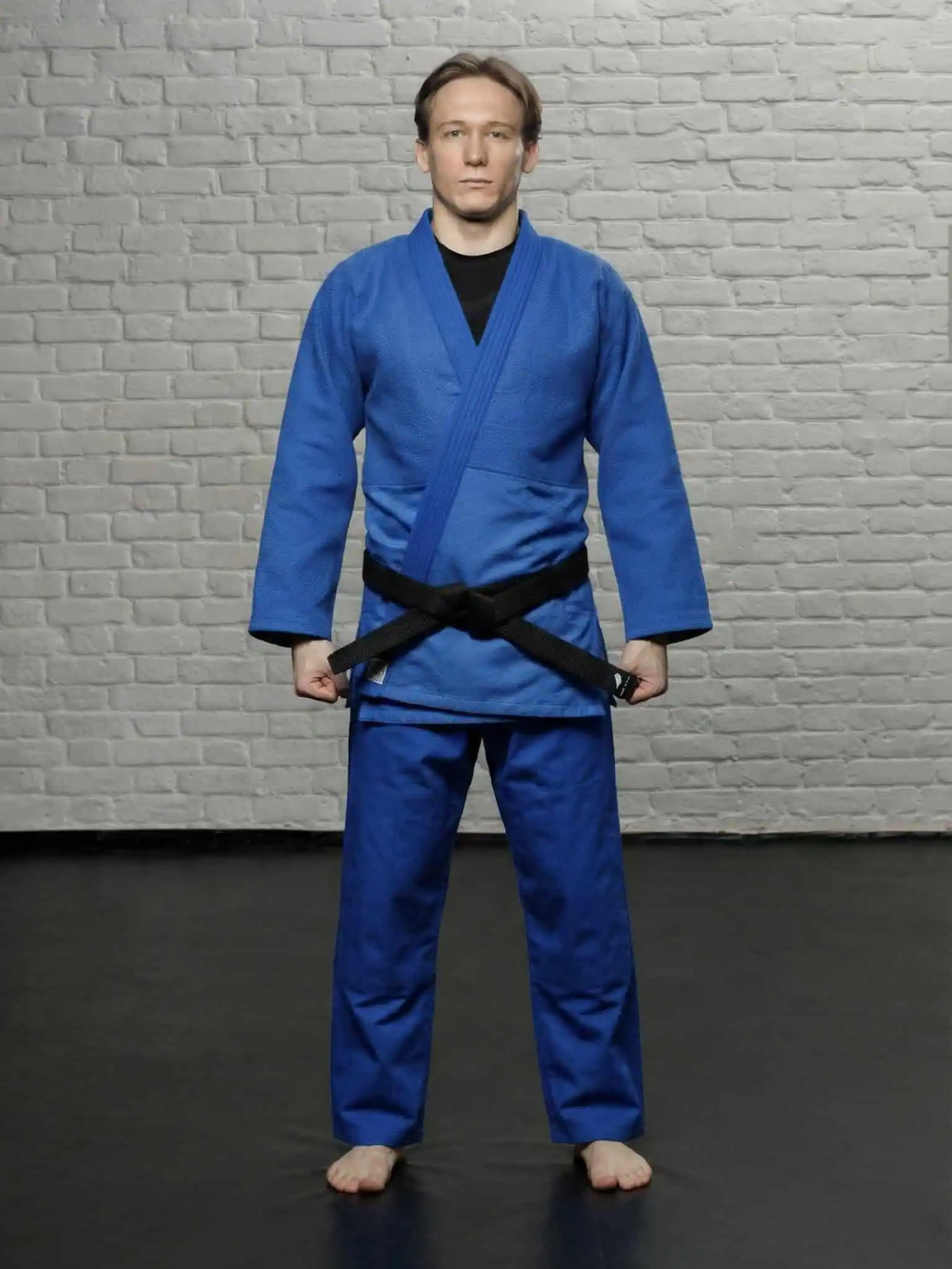 Спортсмен в синей куртке кайтоги для дзюдо, демонстрация комфортной посадки в полный рост на татами