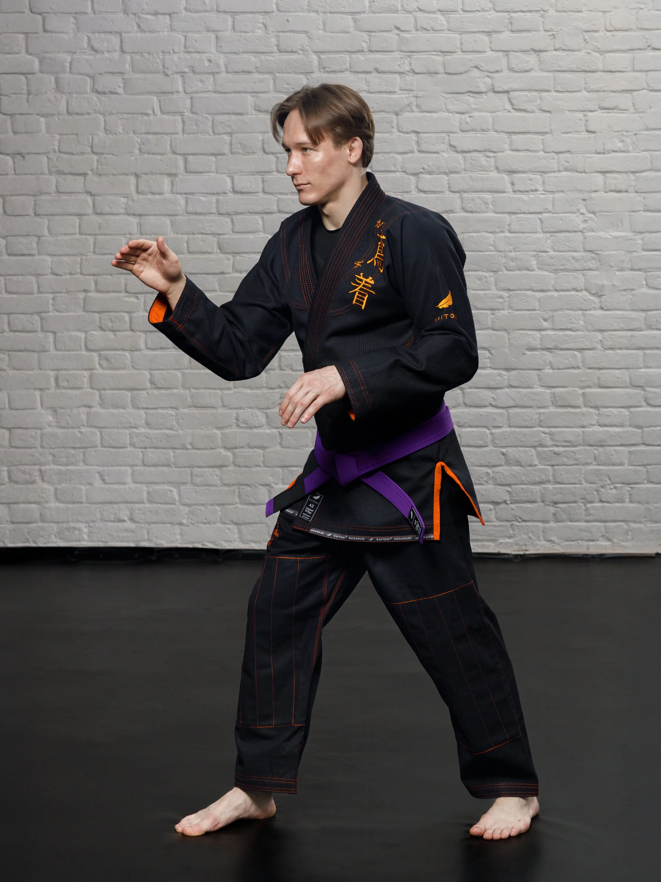 Боевая стойка в черном кимоно с оранжевым дизайном KAITOGI
