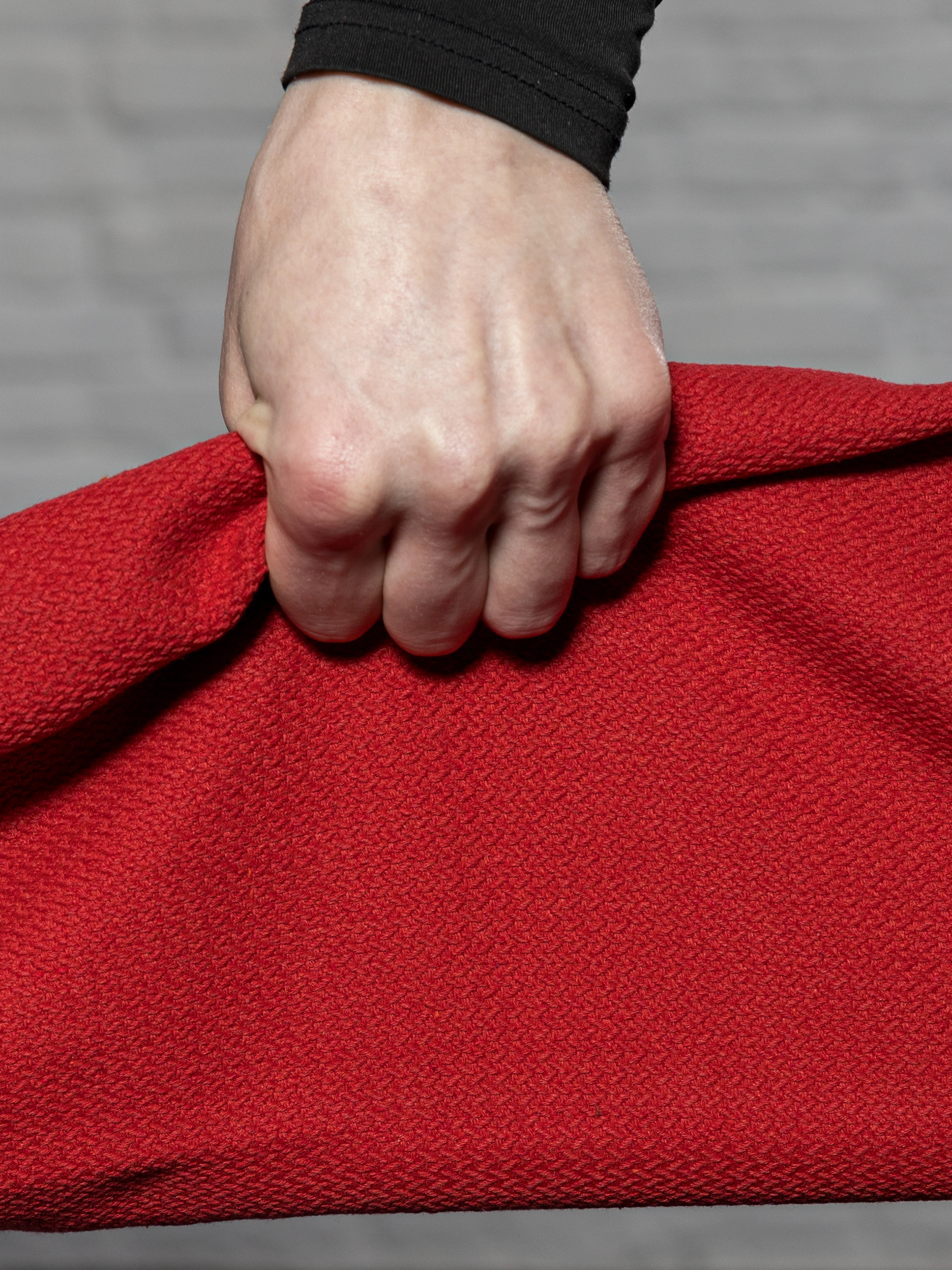 Макро-фото захвата одной рукой за красный тренажер ГРИФ