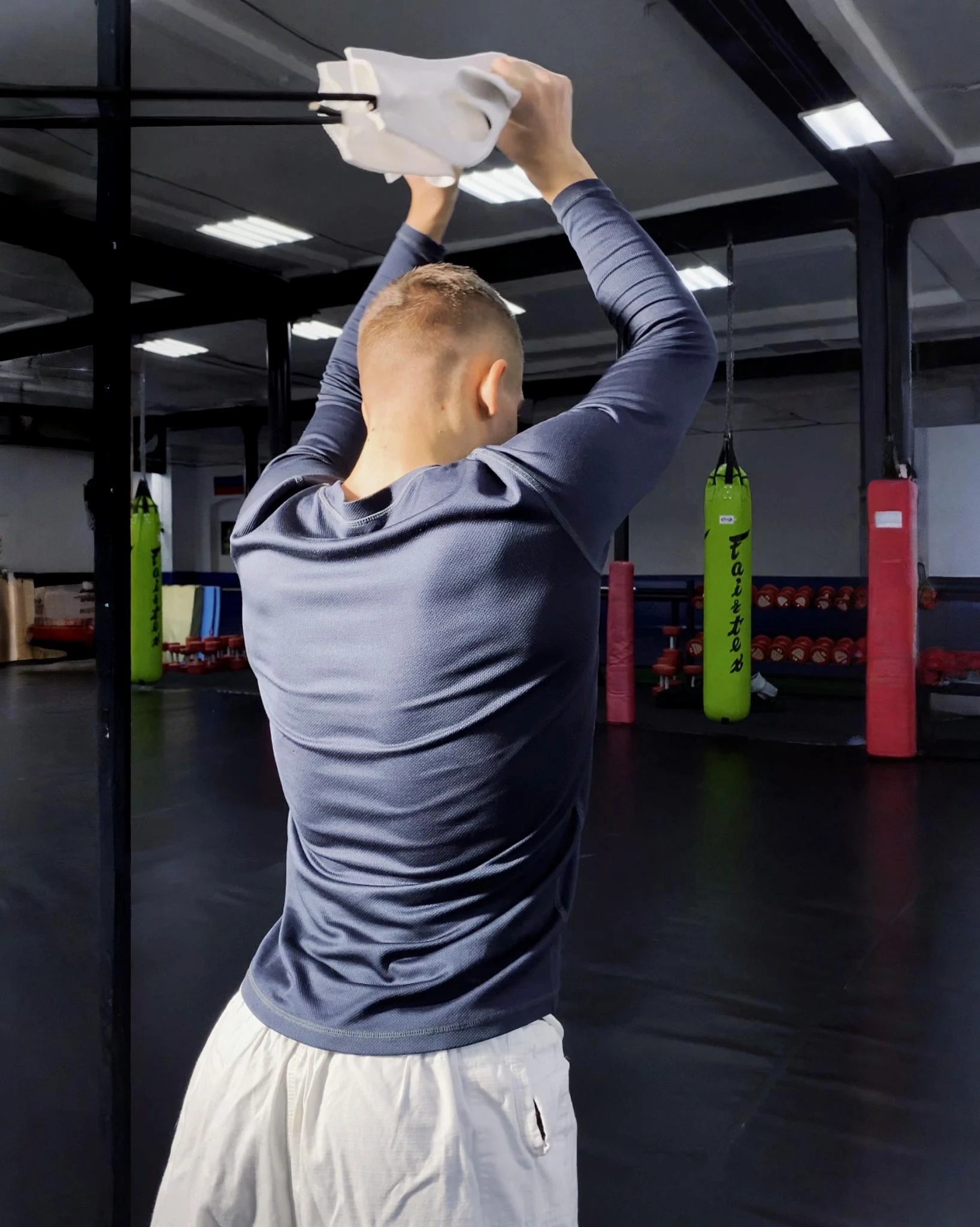 Взрослый атлет выполняет тягу белой резины Учикоми со спины для развития мышц корпуса