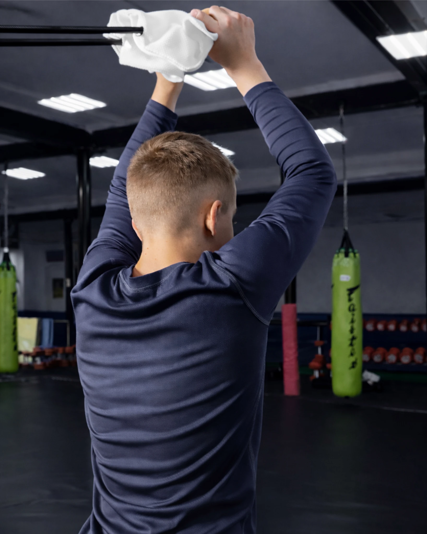 Юный спортсмен выполняет тягу белой резины Учикоми со спины для укрепления мышц