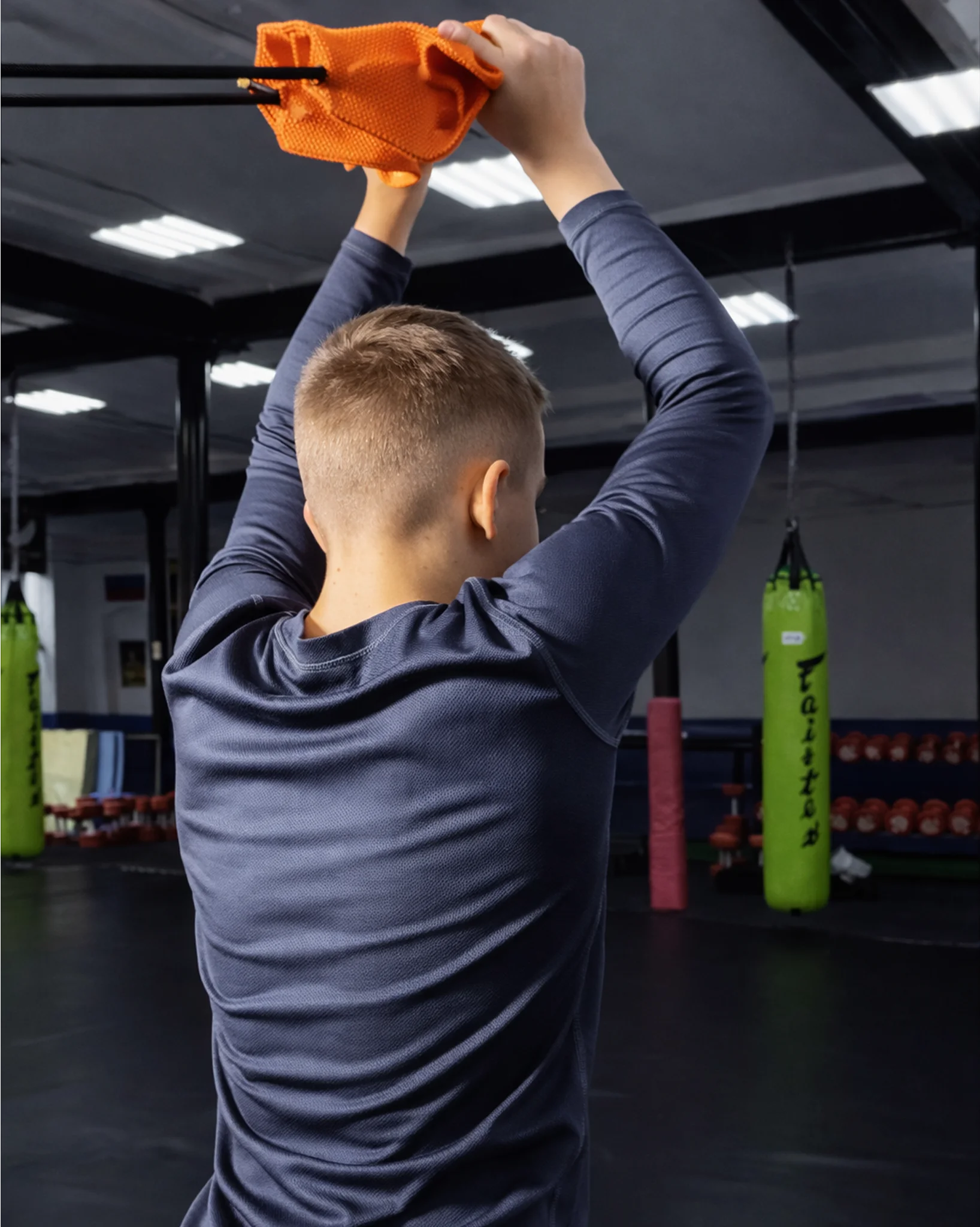 Функциональная тяга оранжевой резины со спины у шведской стенки