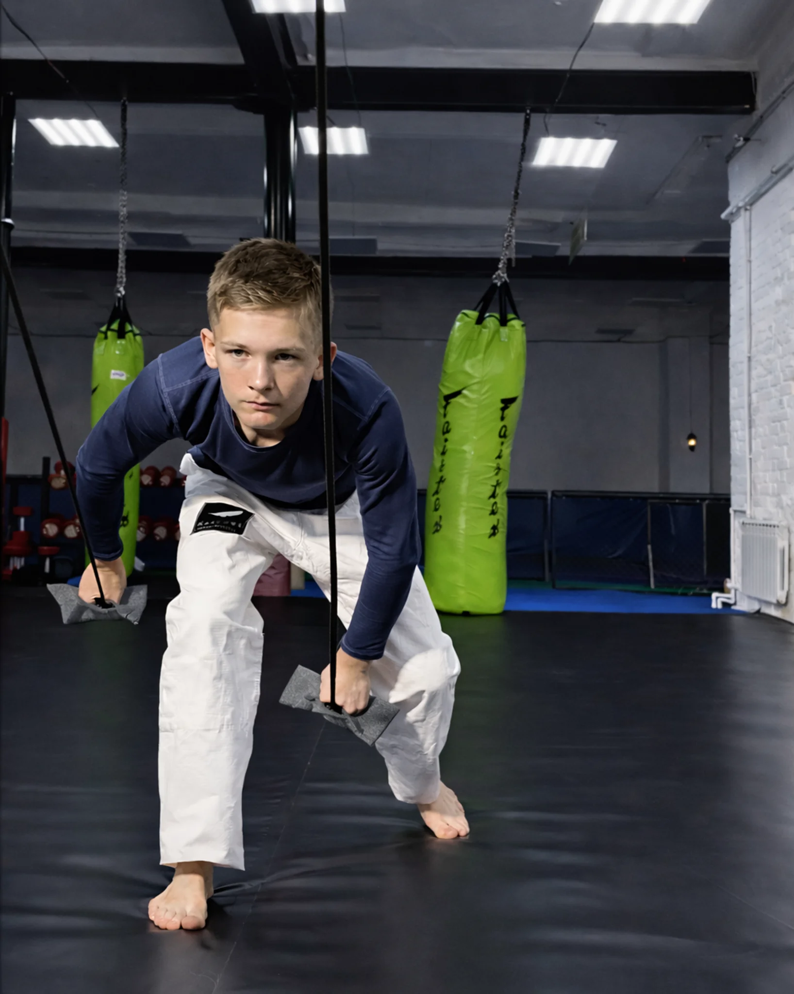 Юный спортсмен укрепляет хват, выполняя тягу серого тренажера вниз