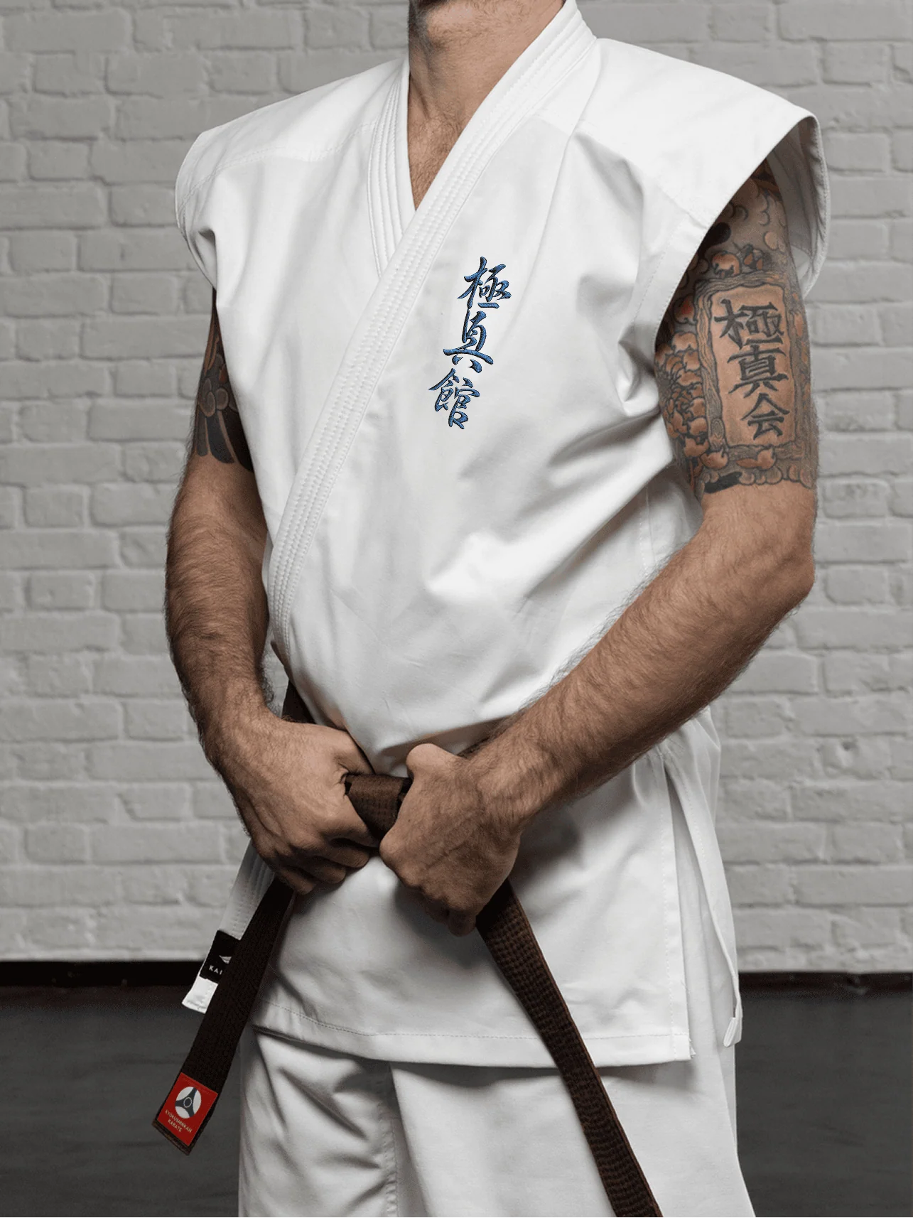 Куртка-жилет К6 Кёкусин-кан (белая) на модели: демонстрация открытых плеч и прецизионной вышивки иероглифа