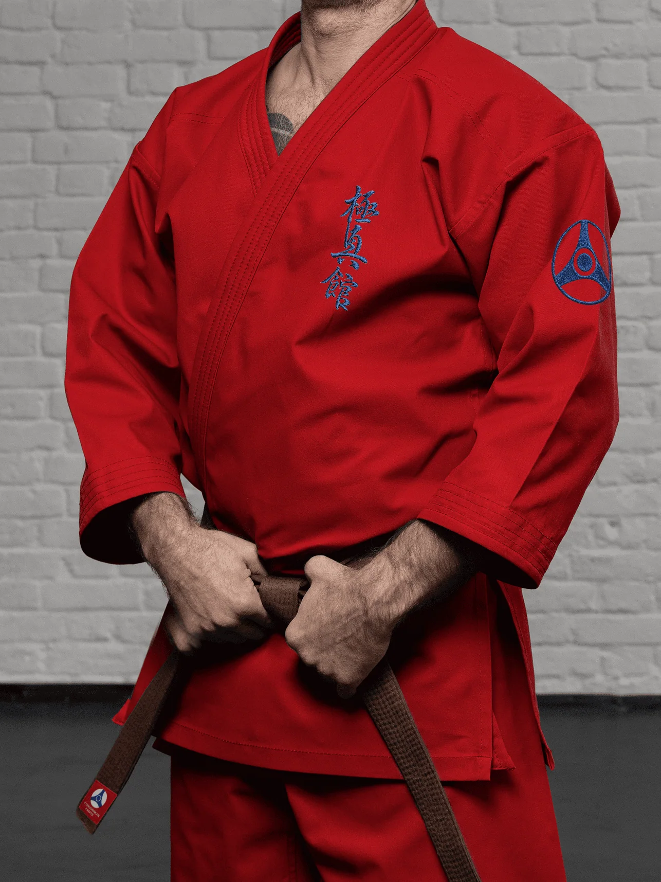 Красная куртка и штаны К3–М5 КАН на спортсмене: детализация вышивки иероглифа на груди и логотипа на плече