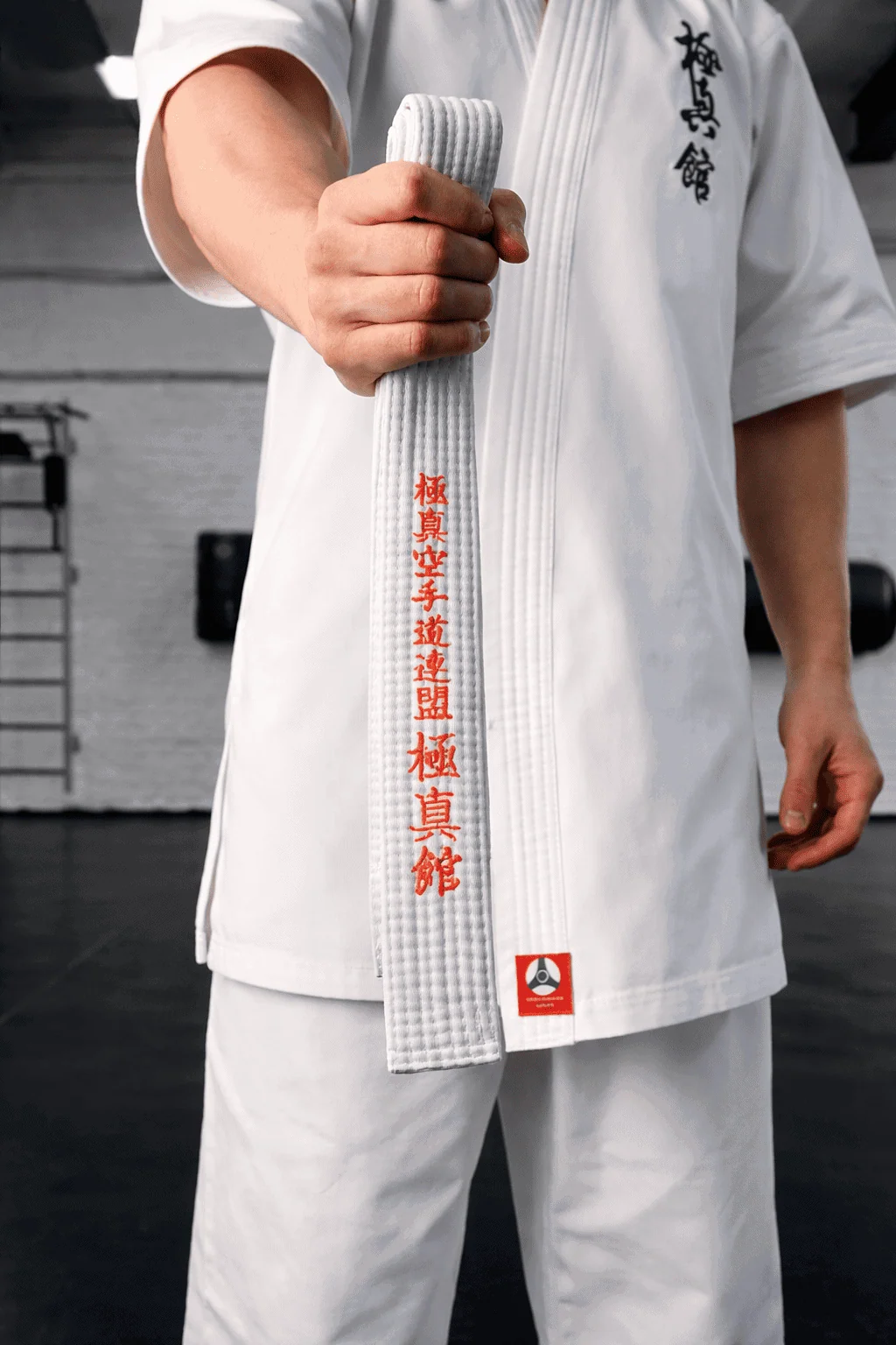 Сложенный белый пояс с оранжевой полосой в руках бойца: первый шаг к мастерству