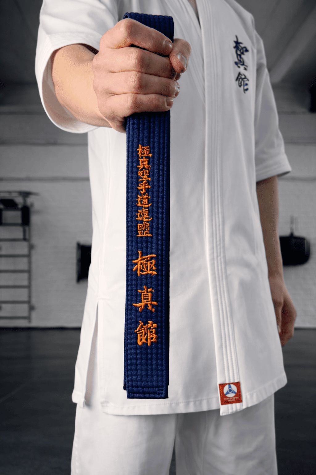 Темно-синий пояс с золотой нитью в руках бойца: 15 лет гарантии на каждое изделие