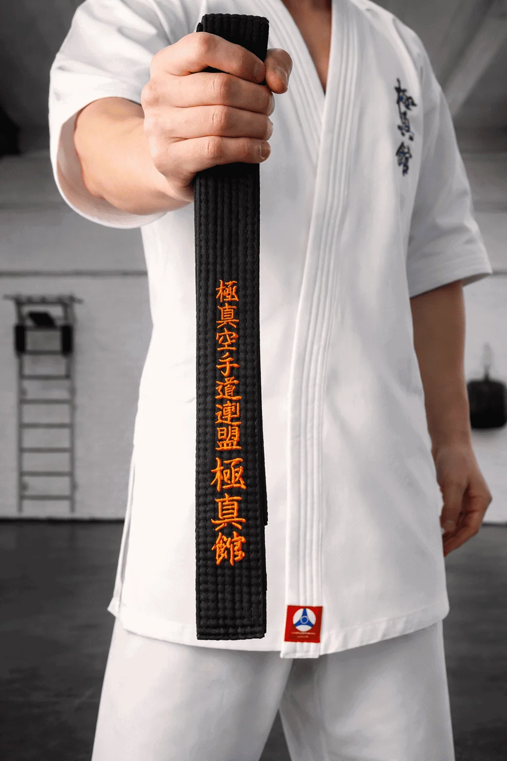 Сложенный черный пояс с золотыми иероглифами в руках: высший уровень мастерства от KAITOGI