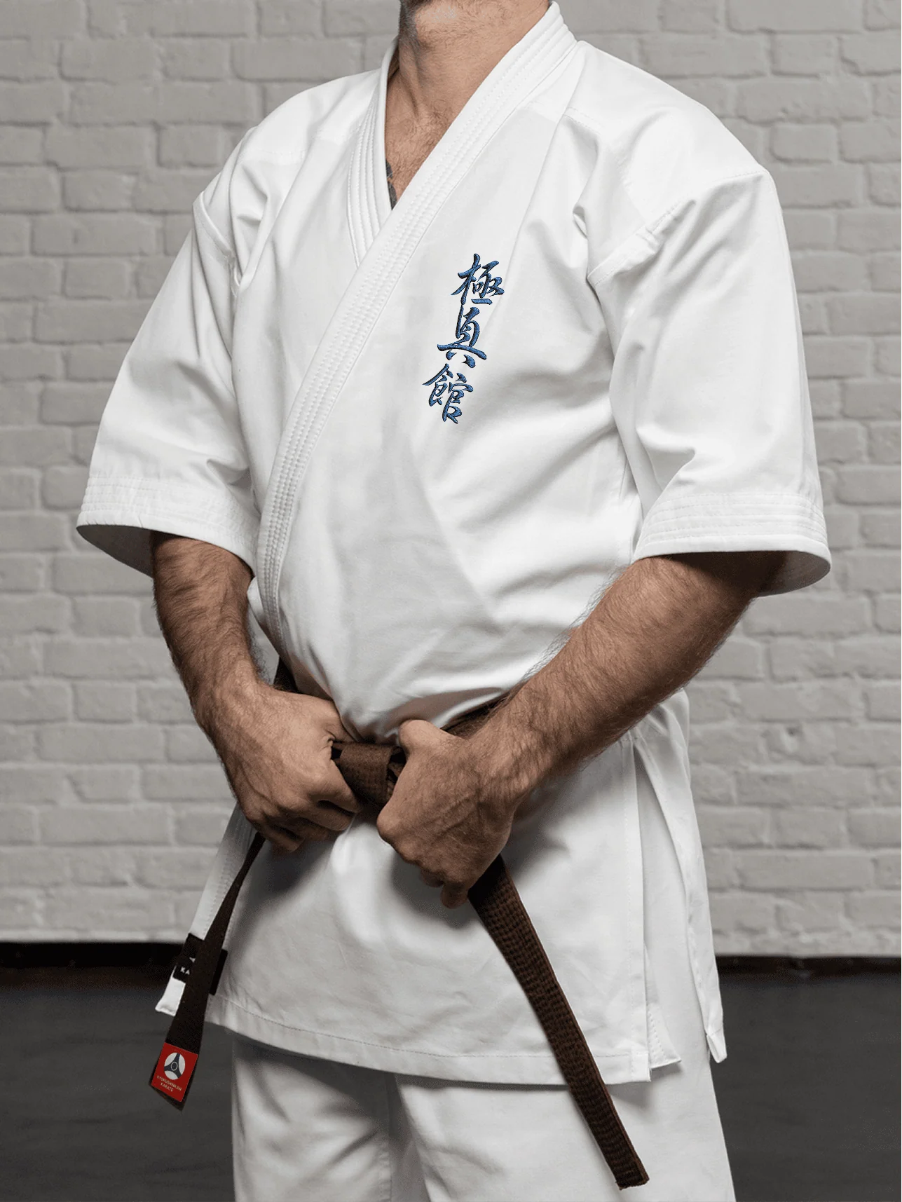 Белая куртка доги К2 стандарт на спортсмене: демонстрация рукава три четверти и аккуратной вышивки на груди