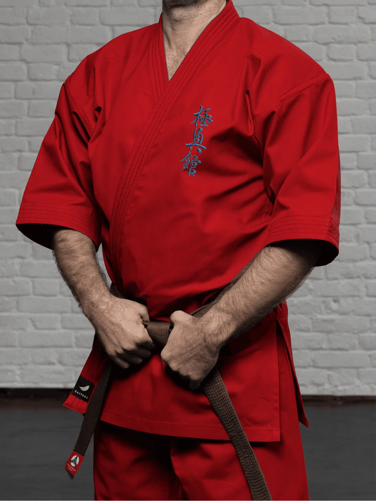 Красная куртка К4 стандарт на спортсмене: чистая линия плеча и аккуратная вышивка Кёкусин-кан на груди