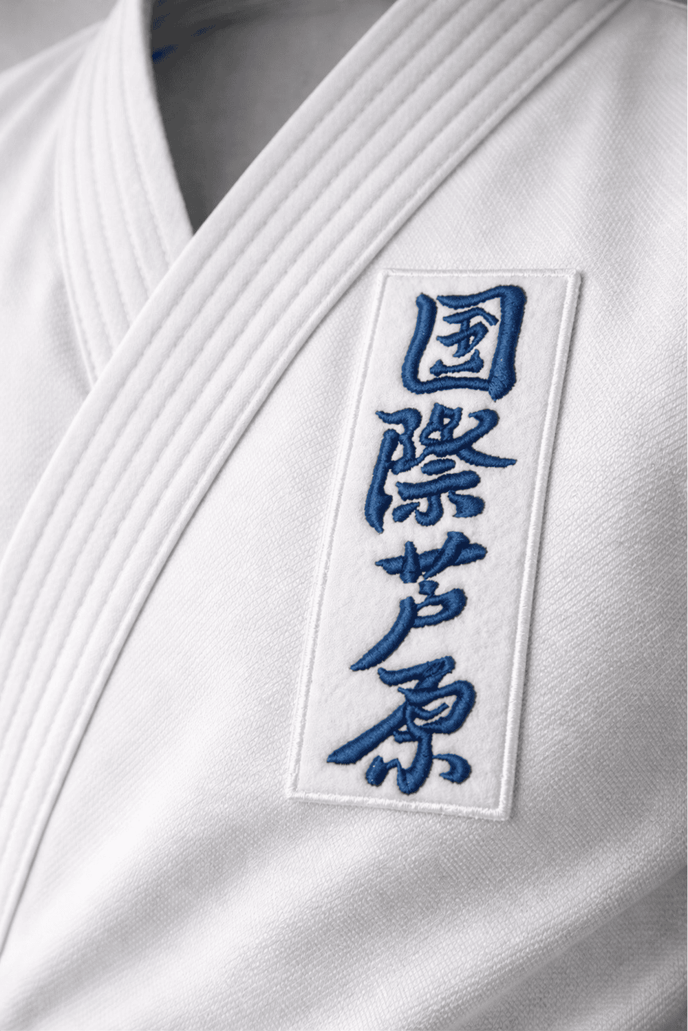 Белый вертикальный шеврон AIKO с синими иероглифами, пришитый на белое кимоно KAITOGI