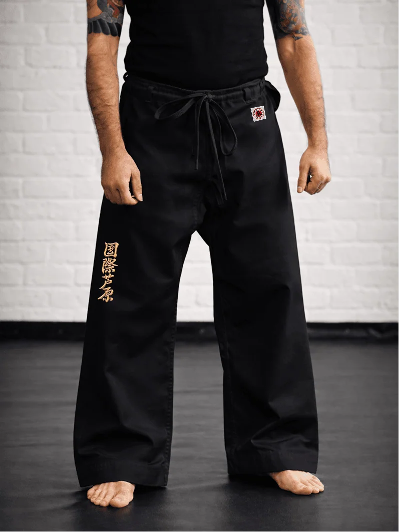 Чёрная модель AIKO М1 на спортсмене: точная посадка, золотая вышивка и фирменная жаккардовая маркировка