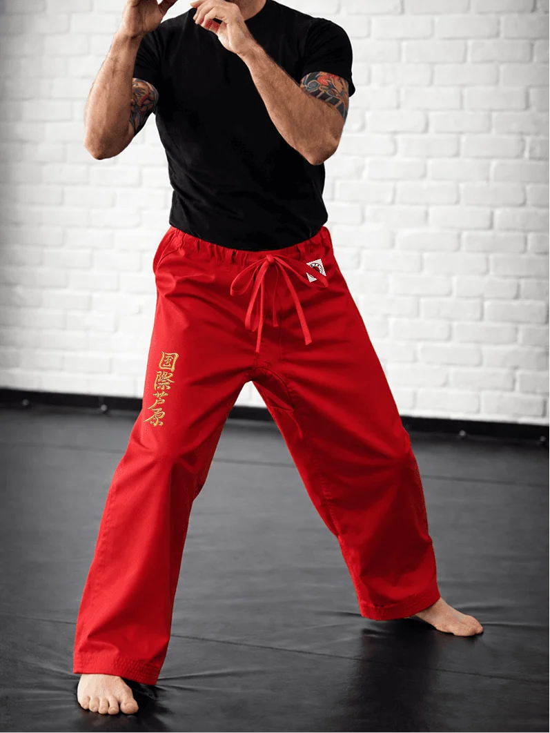 Красные штаны AIKO М2 на модели: длина до щиколотки, золотая вышивка и фирменная отделка