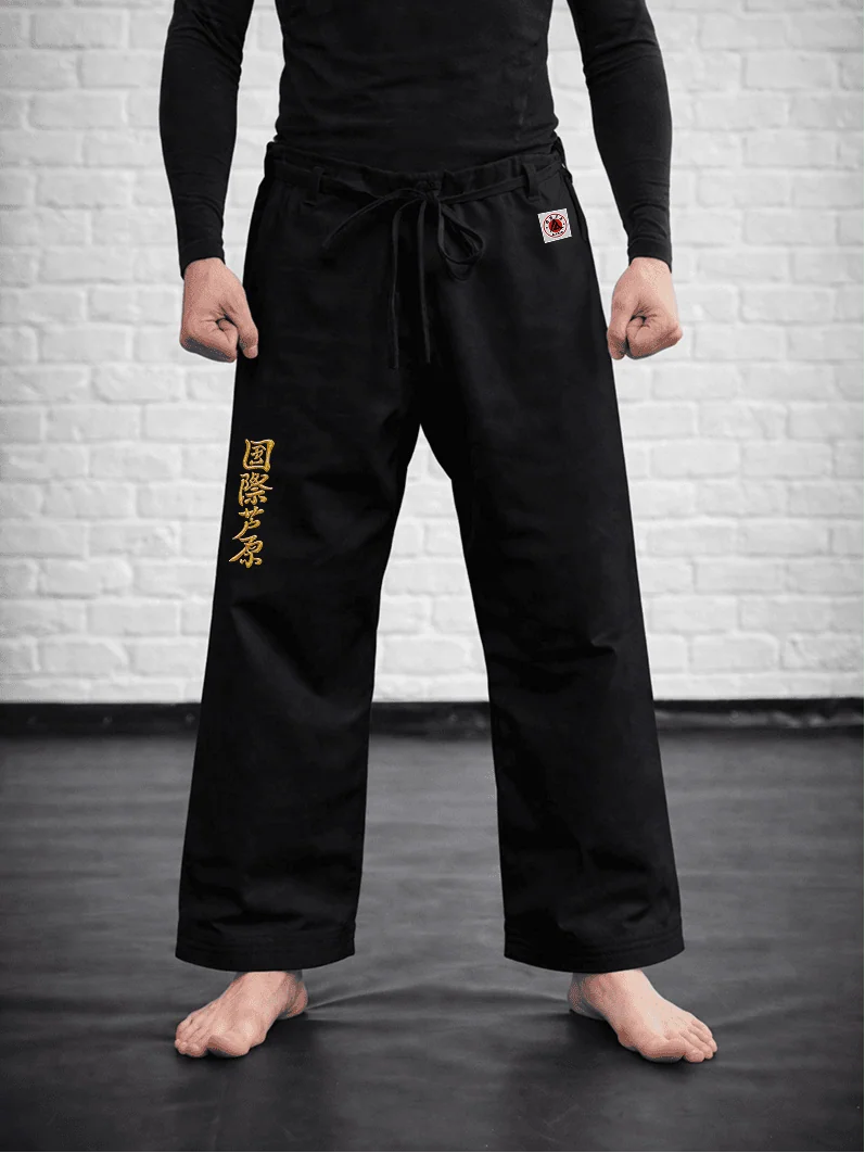 Чёрная модель AIKO М3 на спортсмене: длина выше щиколотки, золотая вышивка и фирменная жаккардовая маркировка