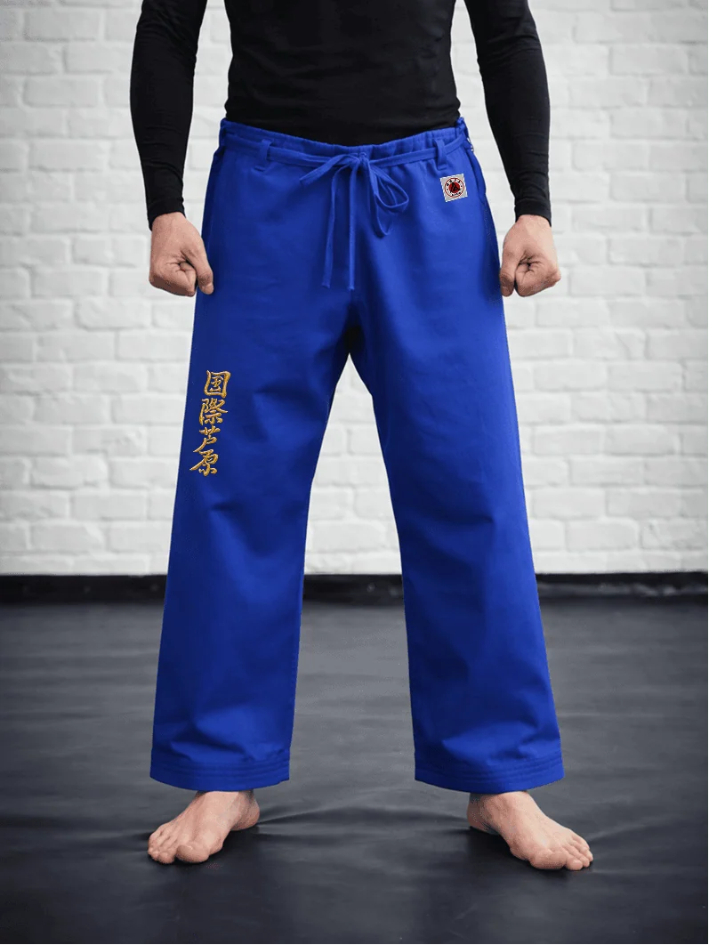 Синяя модель AIKO М3 на спортсмене: укороченный силуэт, золотая вышивка Ашихара-карате и жаккардовый логотип