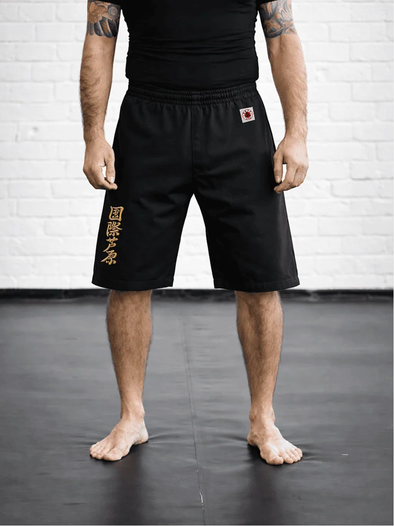 Чёрная модель AIKO М5 на резинке на спортсмене: короткий спортивный формат, золотая вышивка и фирменный жаккардовый знак