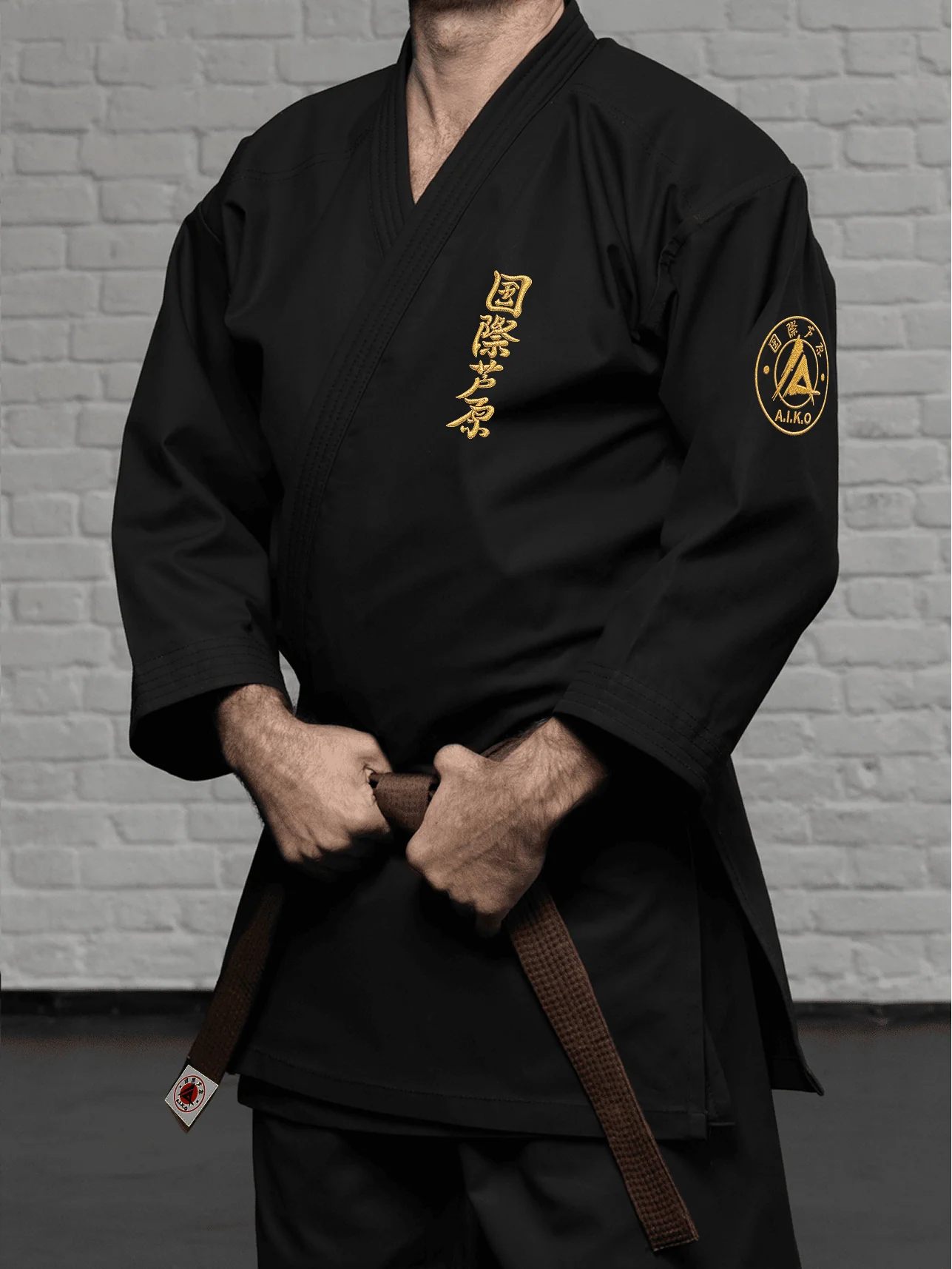 Чёрная куртка AIKO К1 «Наследие» на спортсмене: золотой кандзи, золотая канку A.I.K.O. и плотная посадка классической модели