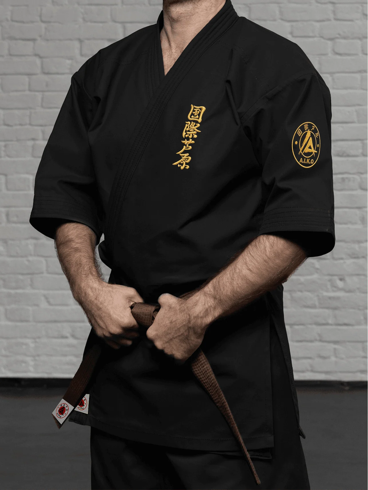 Чёрная куртка AIKO К2 «Наследие» на спортсмене: рукав ниже локтя, золотой кандзи и золотая канку A.I.K.O.