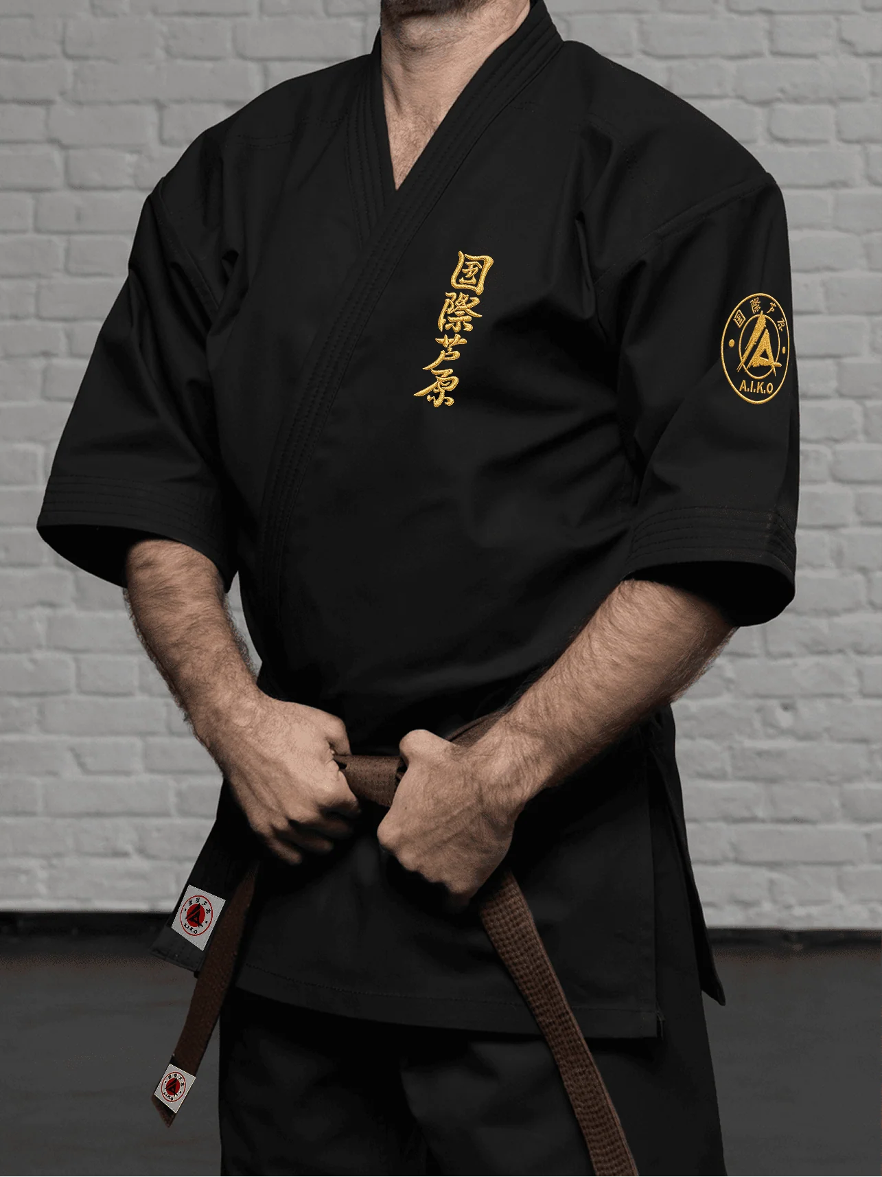 Чёрная куртка AIKO К4 «Наследие» на спортсмене: рукав ниже локтя, золотой кандзи и золотая канку A.I.K.O. при укороченном подоле