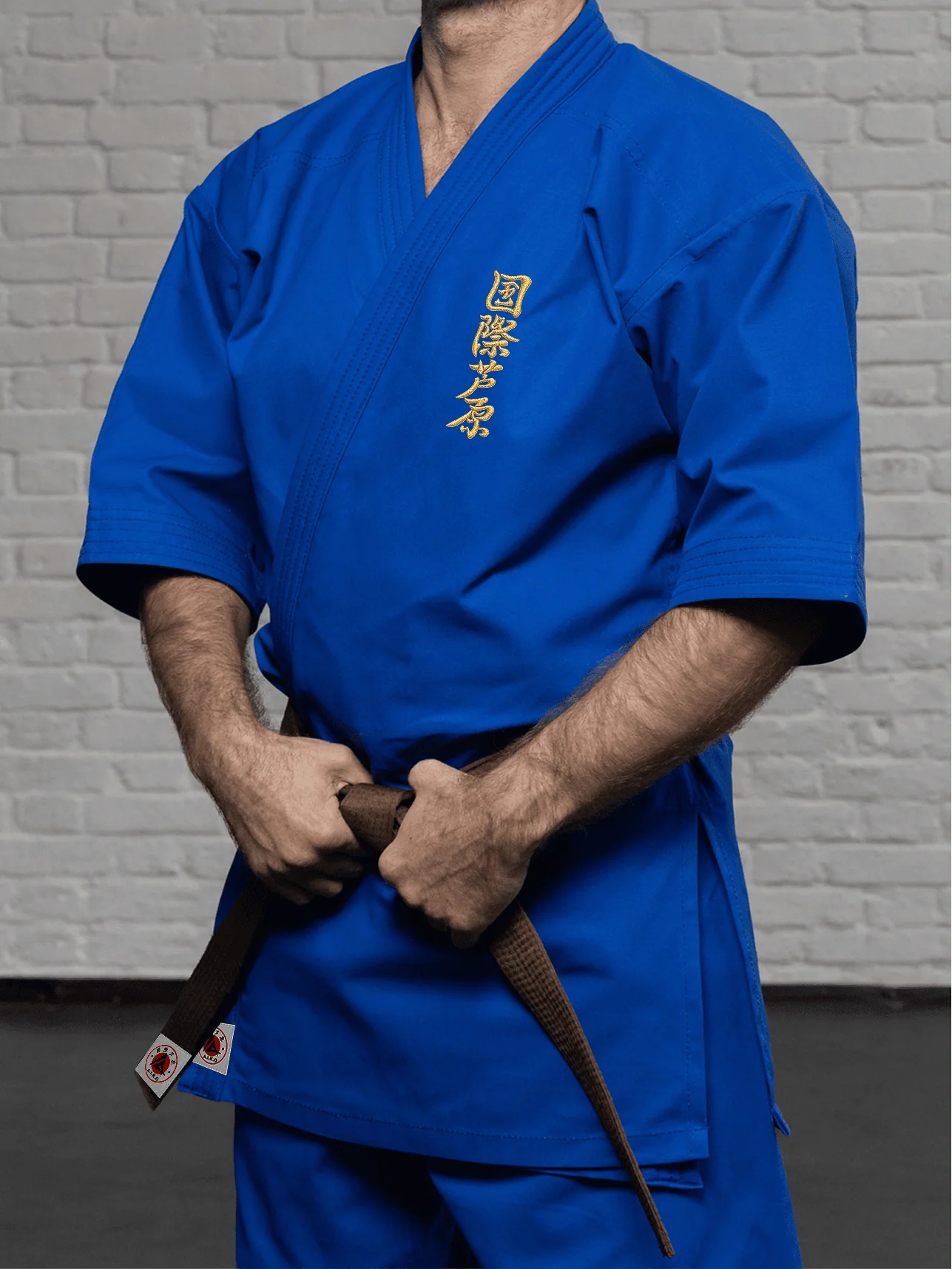 Синяя куртка AIKO К2 «Стандарт» на модели: золотой кандзи Ашихара-карате на груди, рукав 3/4 до середины предплечья и чистое плечо