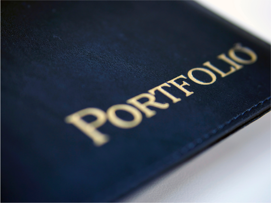 Close-up of a dark leather portfolio cover with the word 'PORTFOLIO' embossed in gold letters.