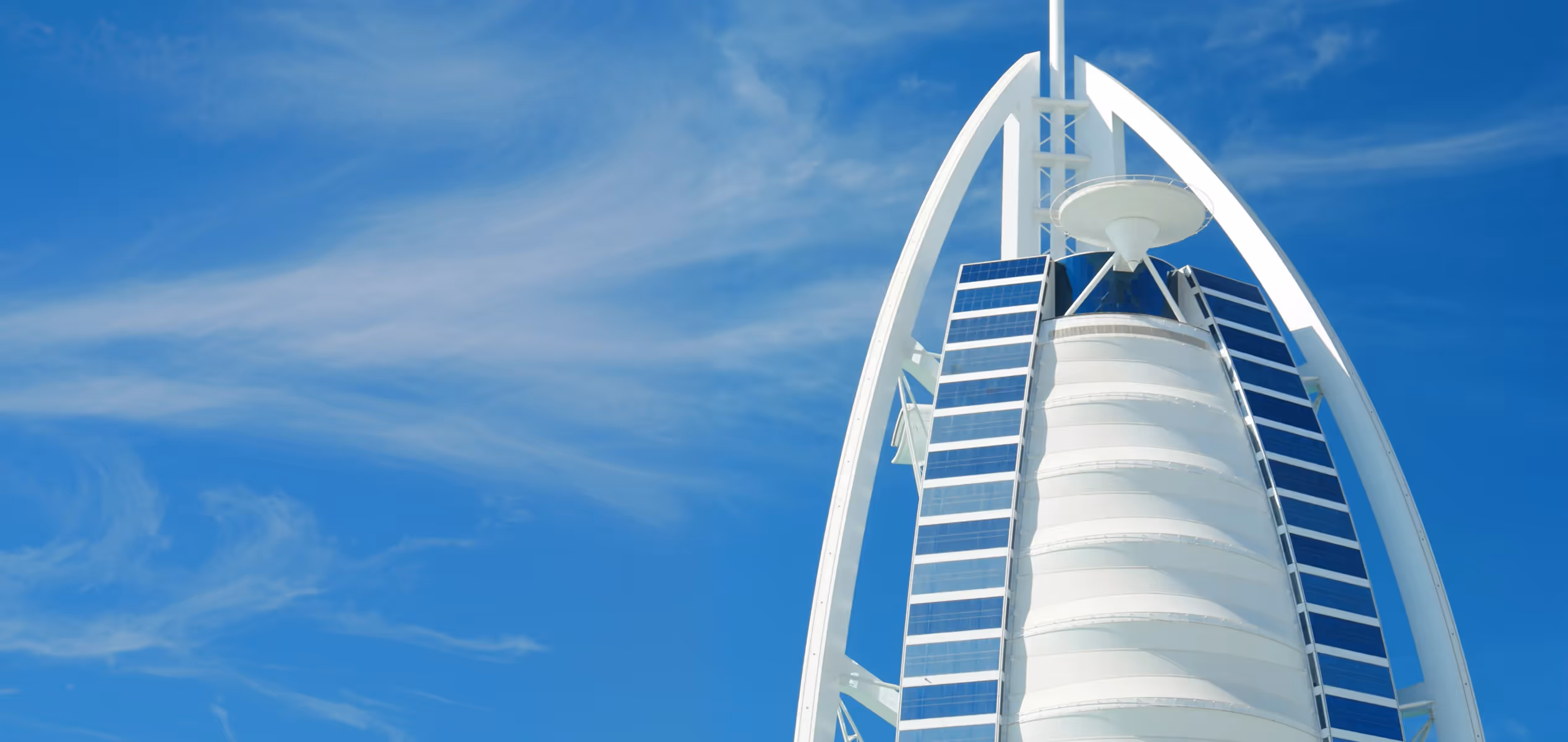 Close-up view of the Burj Al Arab hotel with its white sail-shaped structure under a clear blue sky.