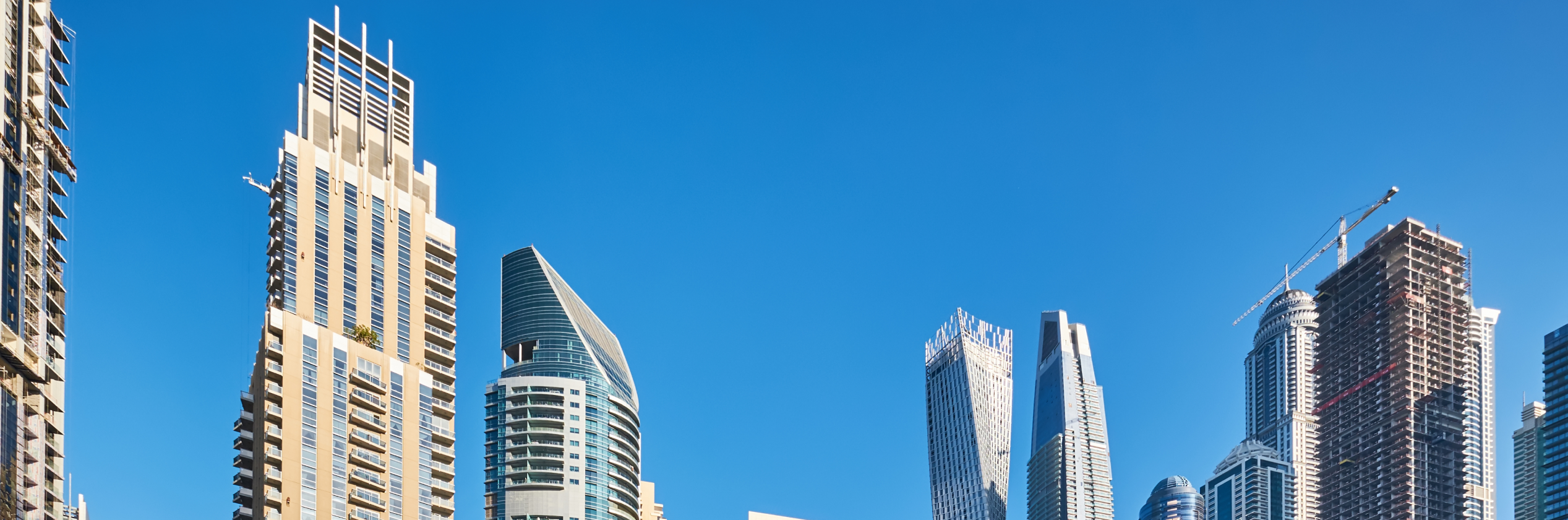 Skyline of modern high-rise buildings in Dubai under a clear blue sky with a text overlay about Dubai's real estate yields.