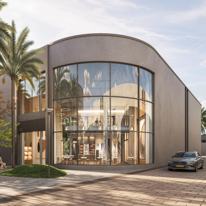 The curved glass frontage of a café building among palms.