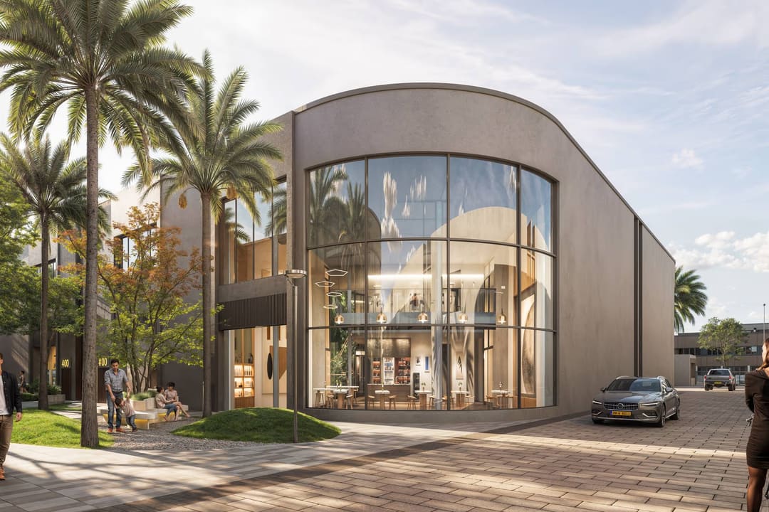 A curved glass corner building among palms.