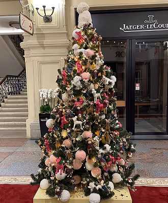 A decorated Christmas tree with pink and white ornaments in the lobby of a shopping mall.