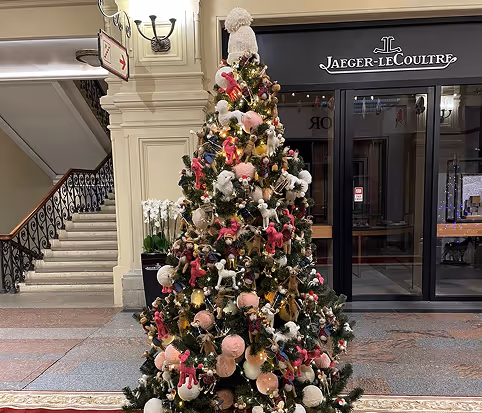Decorated Christmas tree with pink, white and gold ornaments installed indoors.