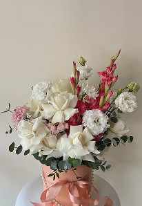 Bouquet of white roses, pink gladiolus, and other flowers arranged in a pink basket with.