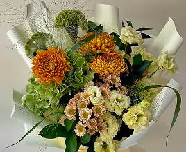 Bouquet of orange chrysanthemums and light green flowers wrapped in white paper.