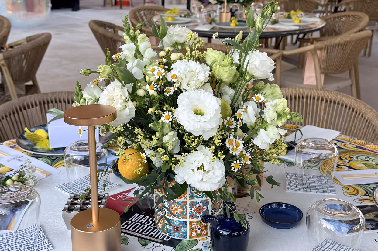 Colorful floral centerpiece with white flowers and lemons on a decorated table at a restaurant.