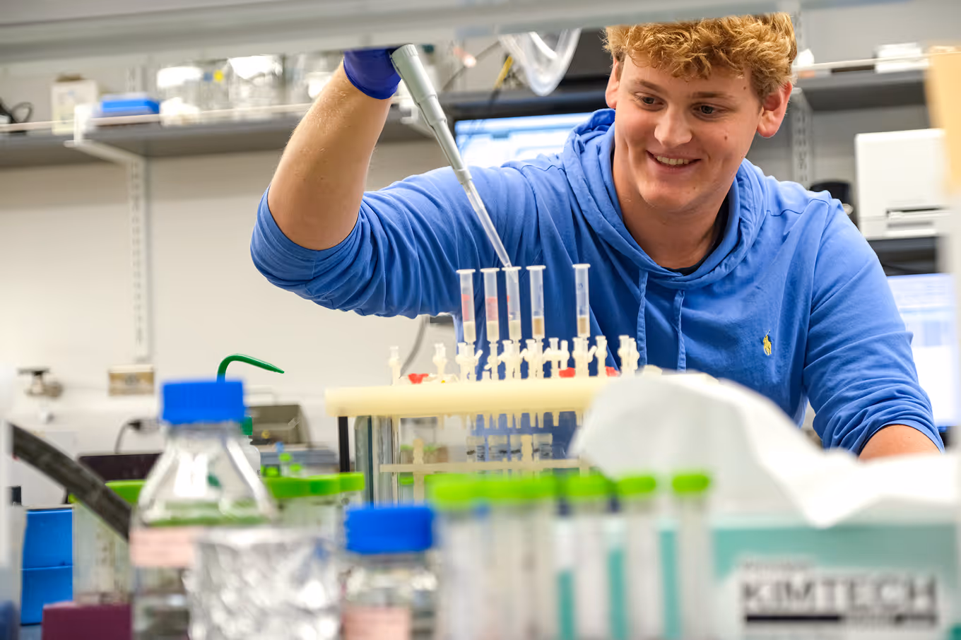 Cary Academy student conducting a science experiment with test tubes and pipette in a research laboratory.
